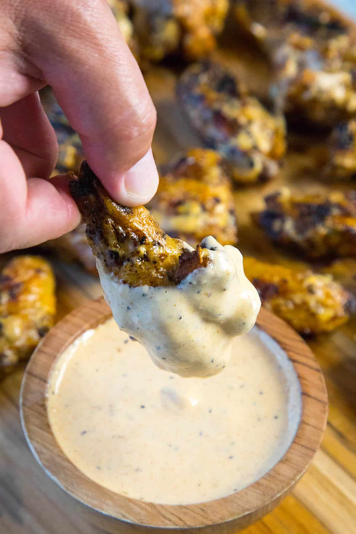 Dipping Brined Grilled Chicken Wings into the Alabama White BBQ Sauce
