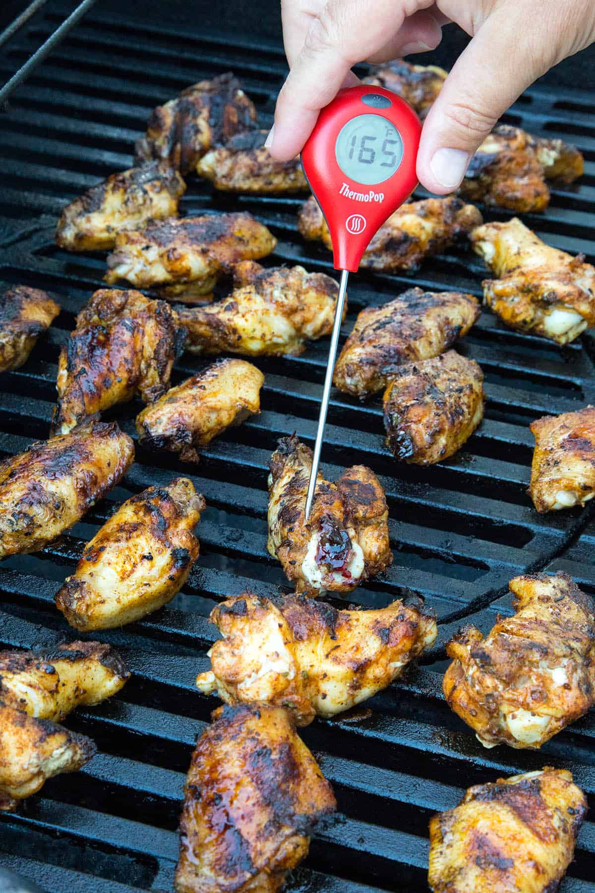 Measuring the internal temperature of the chicken wings. They are done at 165 degrees Fahrenheit.