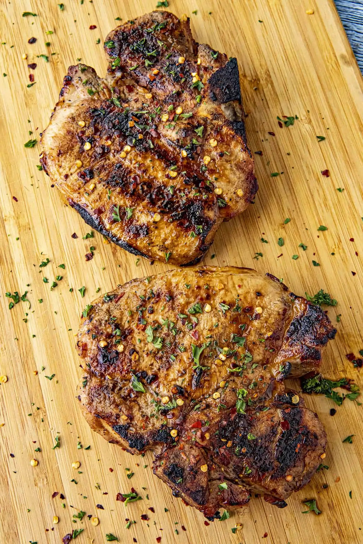 Two juicy bone-in grilled pork chops on a cutting board