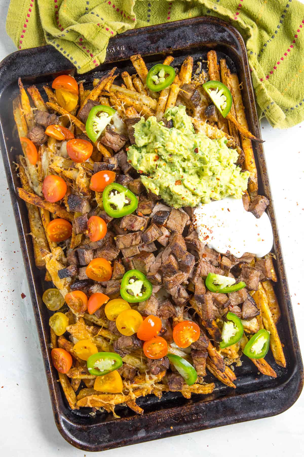Carne Asada Fries on a baking sheet with lots of fixings