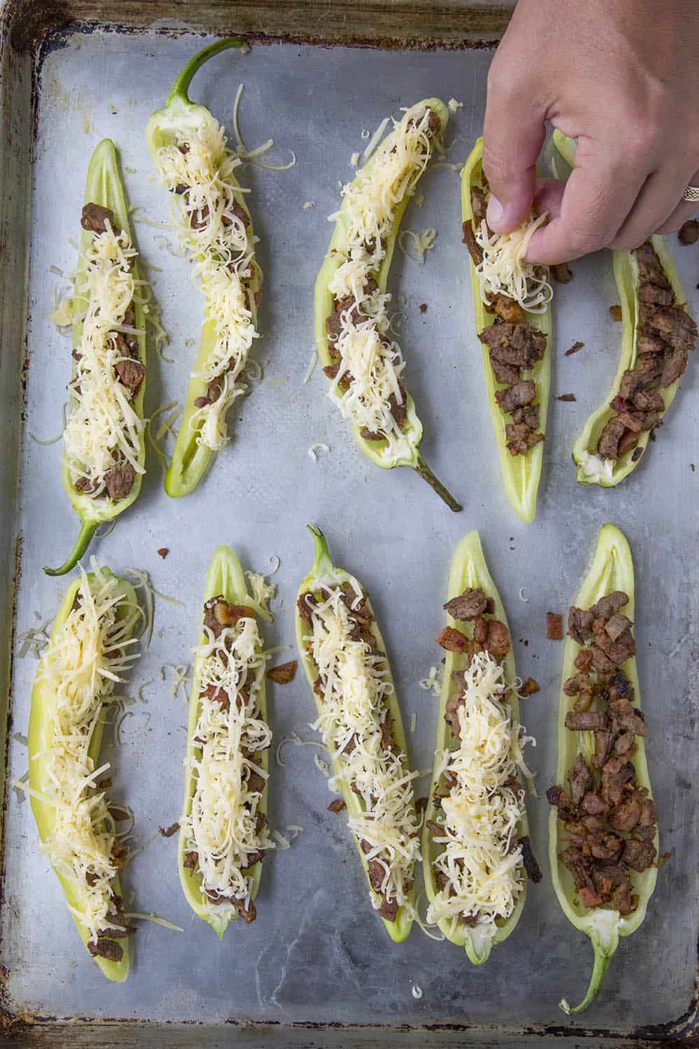 Topping the stuffed banana peppers with cheese