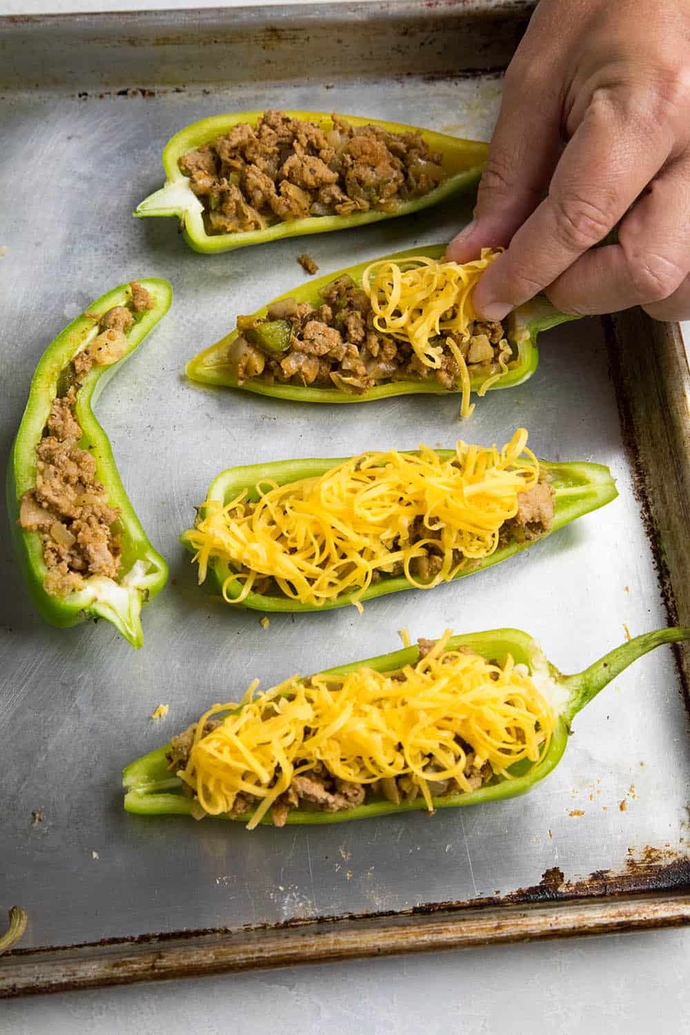 Topping the stuffed Anaheim peppers with cheese