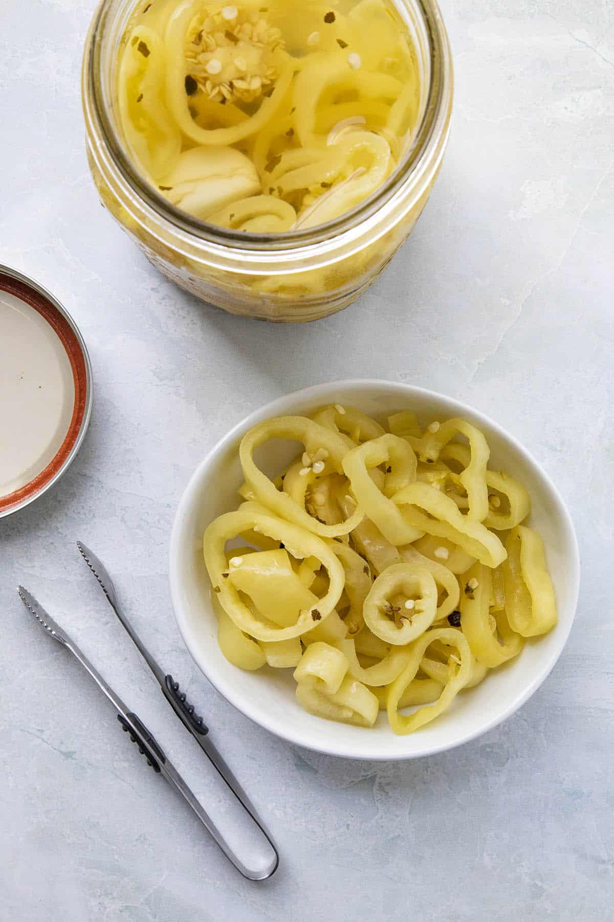 Pickled Banana Peppers in a bowl with tongs, ready to serve