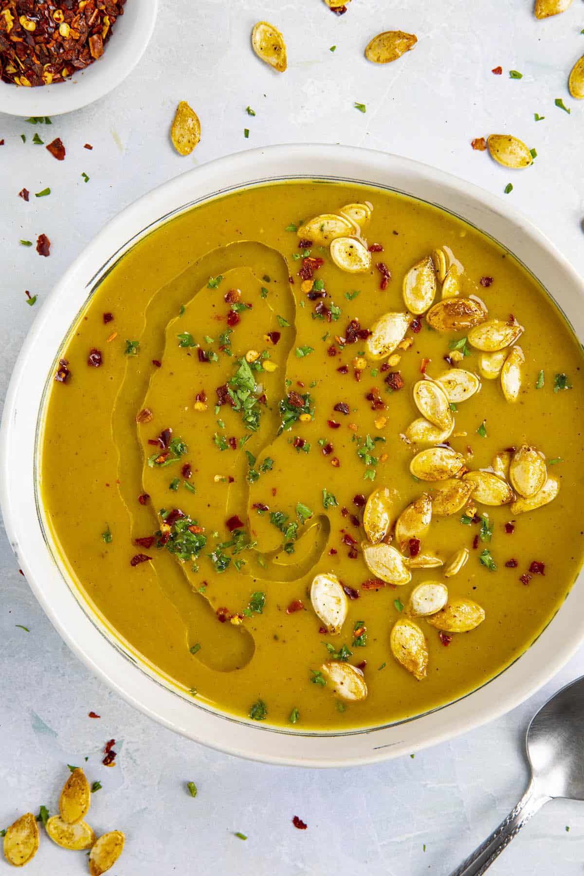 Spicy Pumpkin Soup in a bowl with pumpkin seeds and olive oil swirled over the top