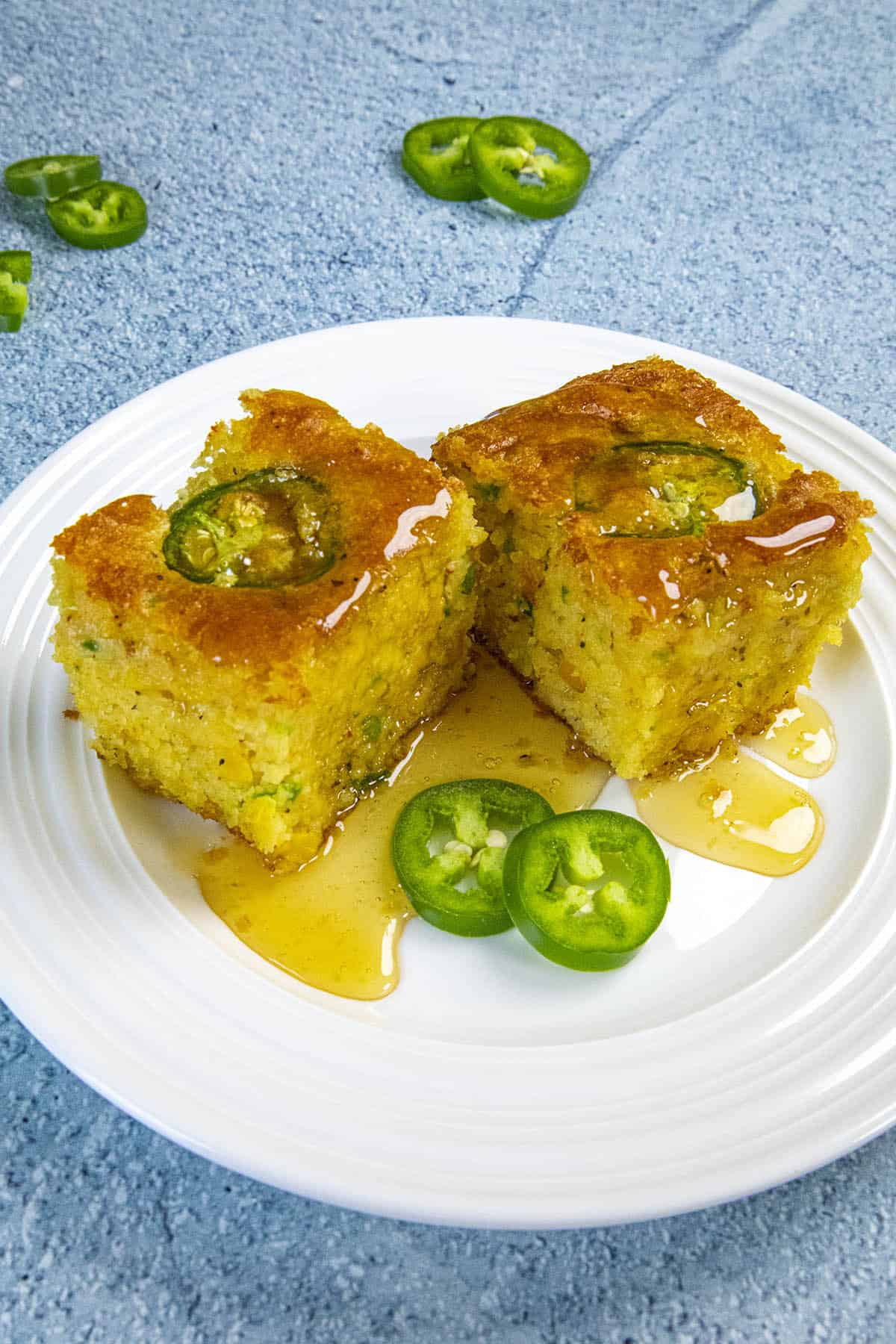 Two slices of Jalapeno Cornbread dripping with honey
