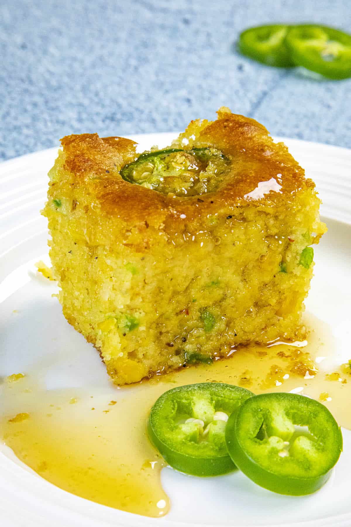 A slice of Jalapeno Cornbread on a plate, dripping with honey