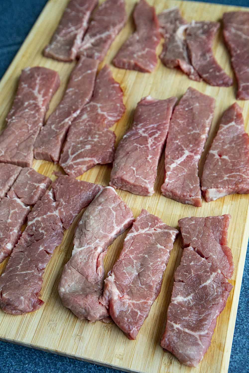 Strips of raw beef on a wooden board