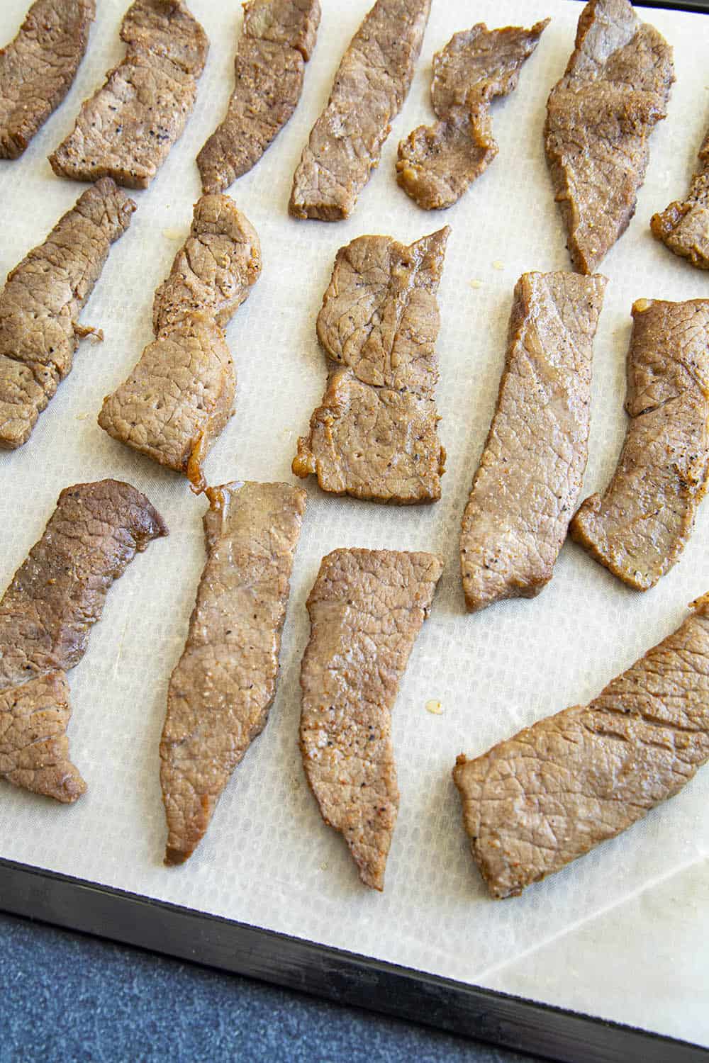 Strips of beef layered out on a tray.