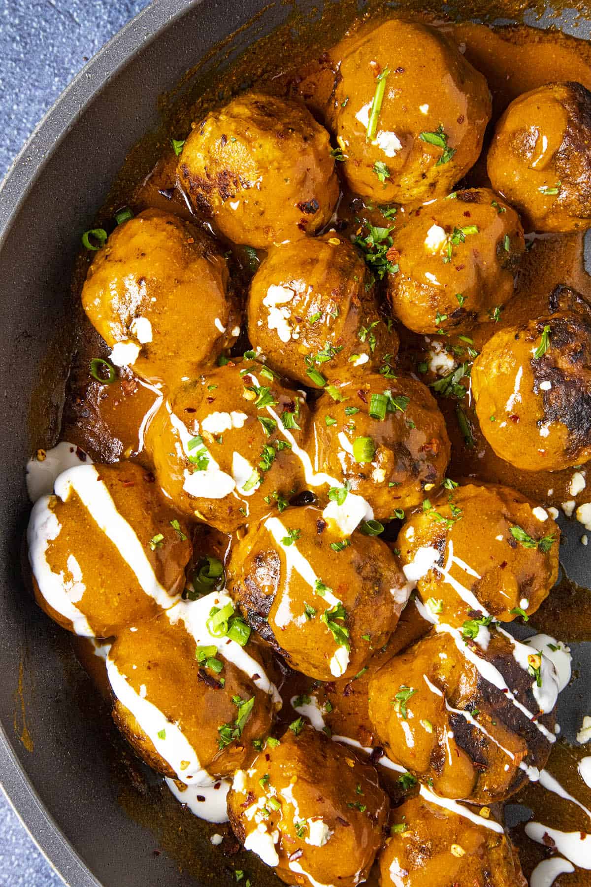 Buffalo Chicken Meatballs on a plate, served up in a pan with blue cheese sauce drizzled over the top