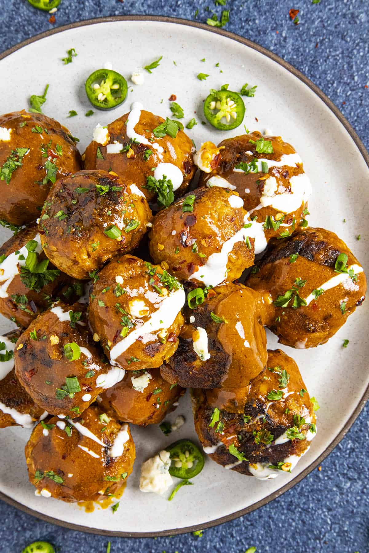 Buffalo Chicken Meatballs on a plate, with blue cheese sauce drizzled over the top