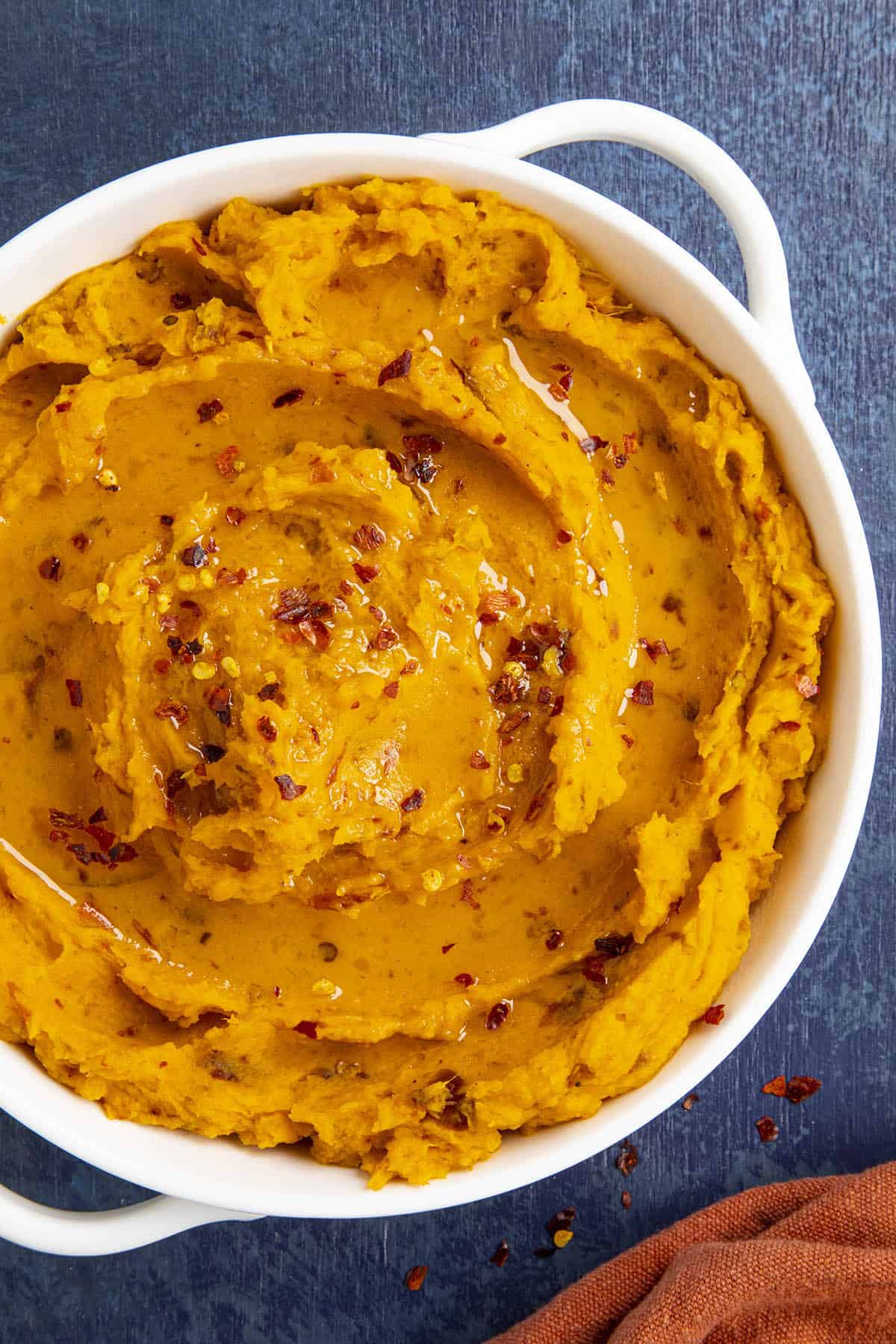 Chipotle Mashed Sweet Potatoes in a bowl, topped with chili flakes and olive oil