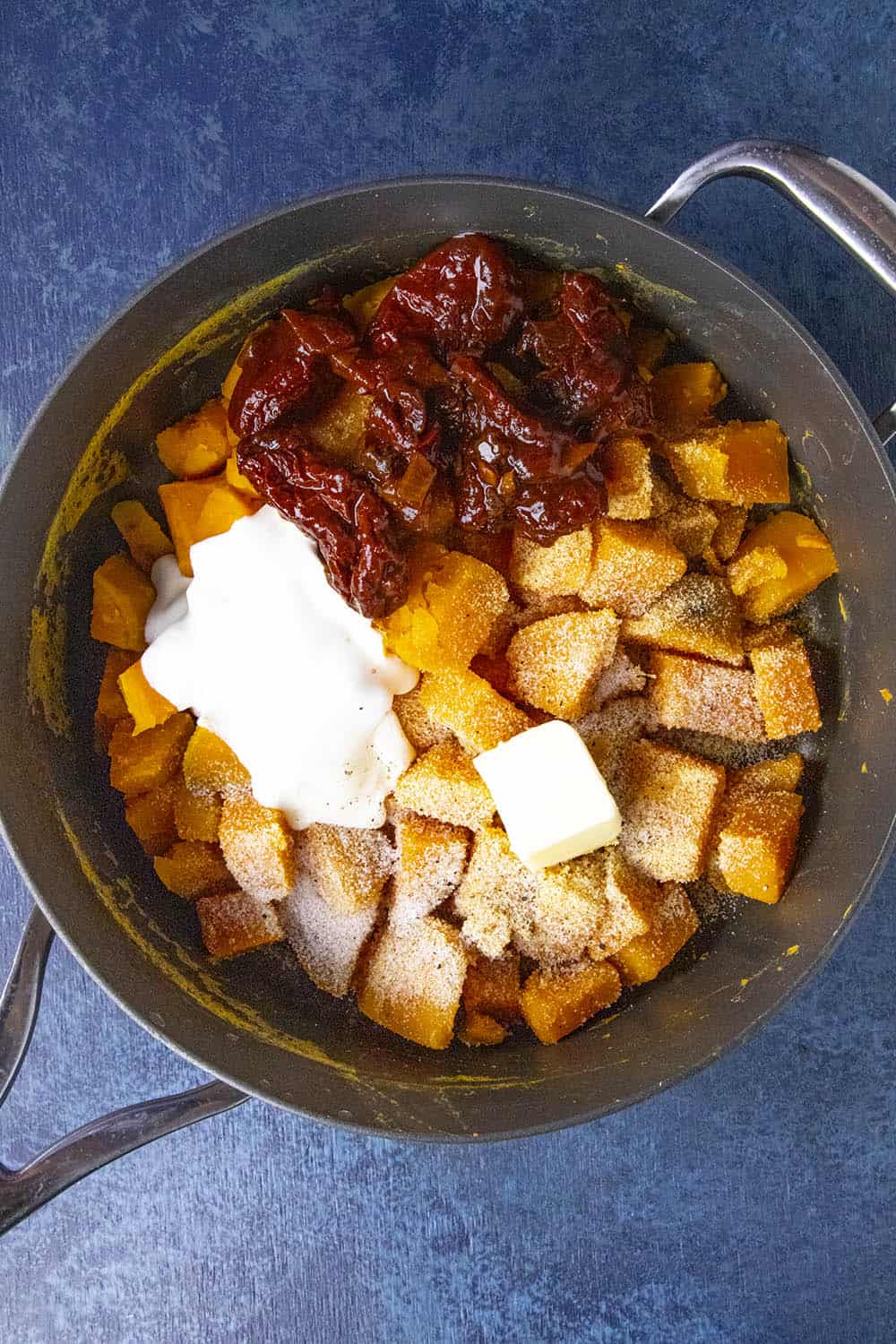 Boiled sweet potatoes in a pot with chipotles, crema, butter and seasonings, ready to mash