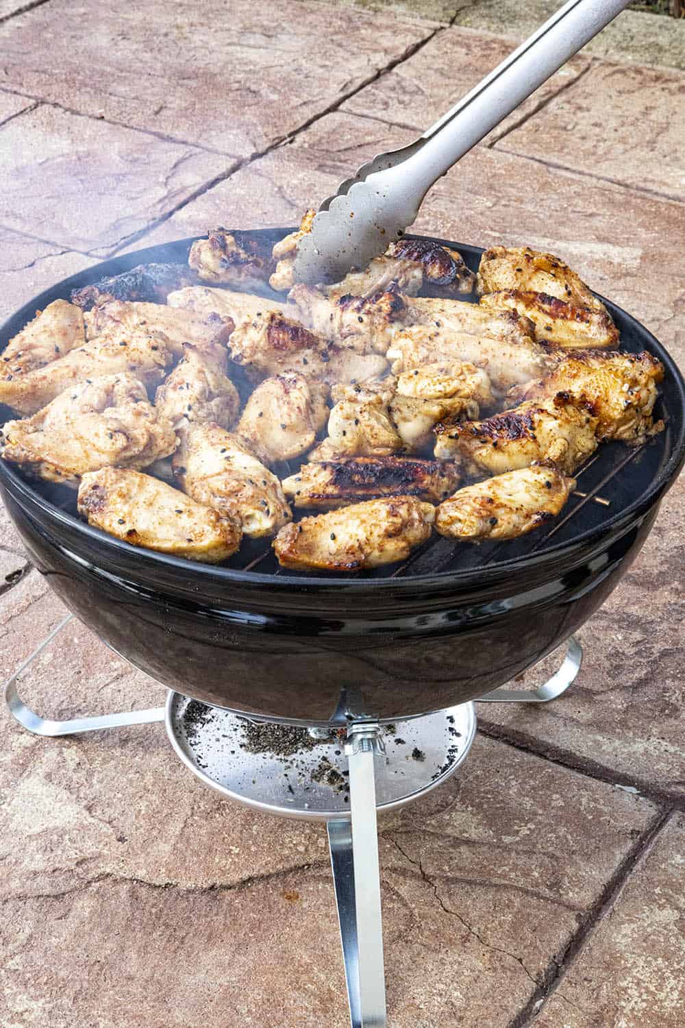 Flipping the grilled chicken wings on the grill.