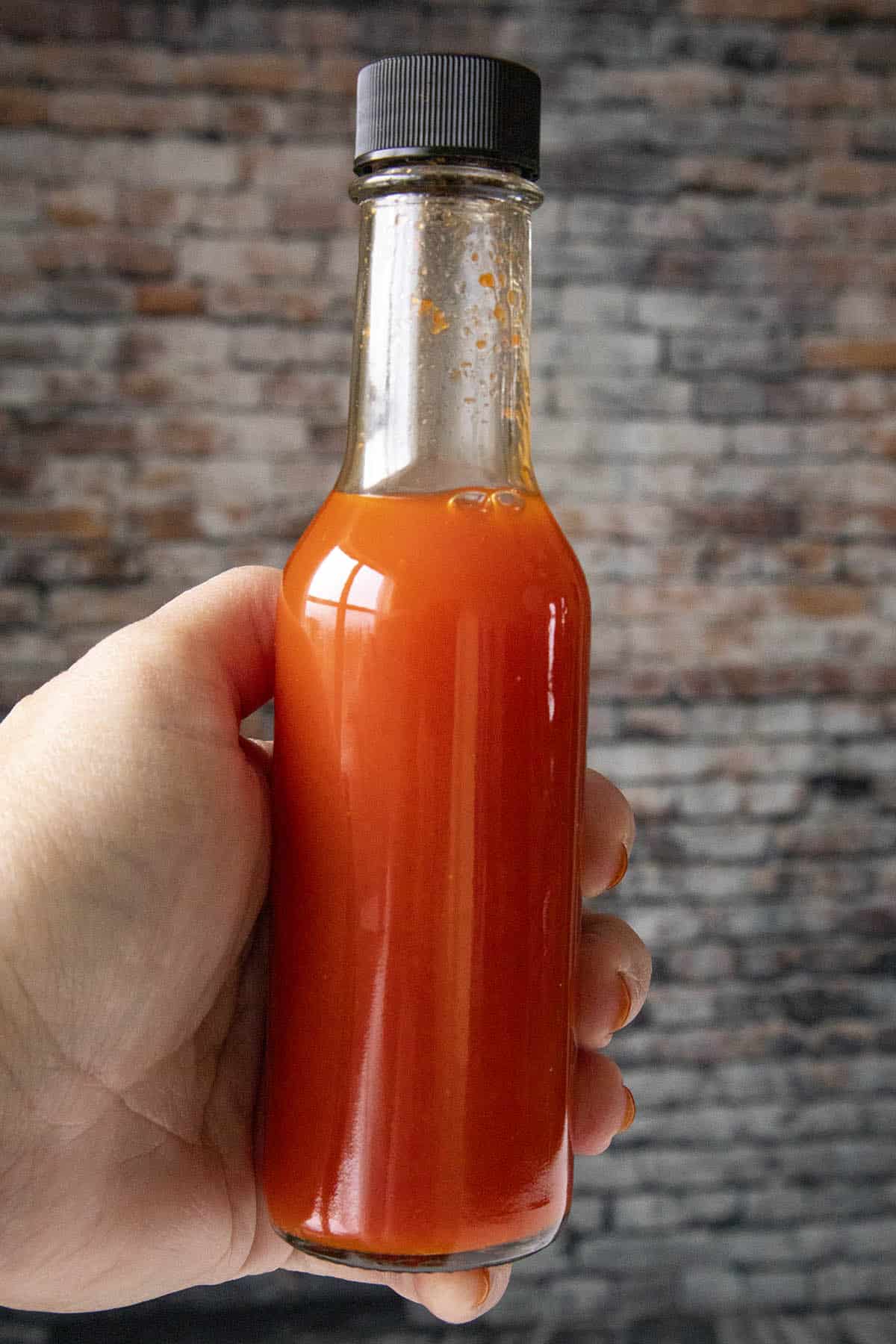 Holding a bottle of my newly made Red Serrano Hot Sauce