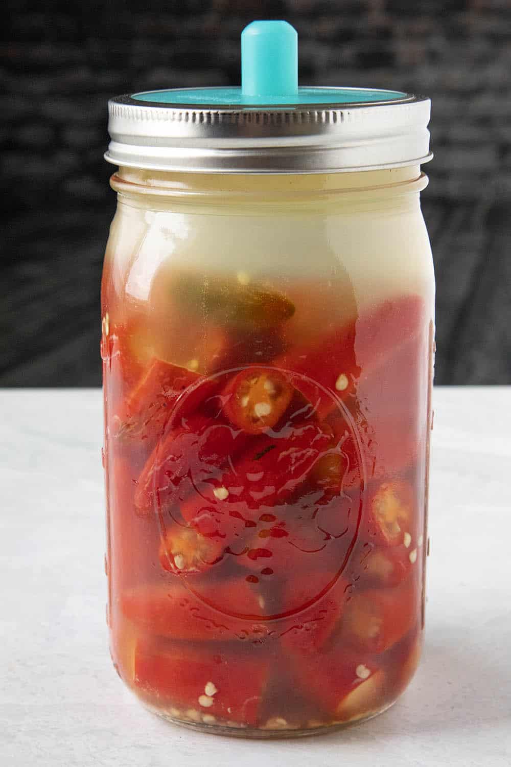 Fermenting red serrano peppers in a jar with brine
