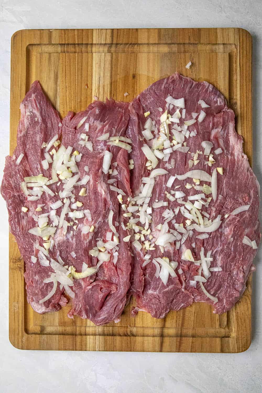 Adding onion and garlic to the flank steak