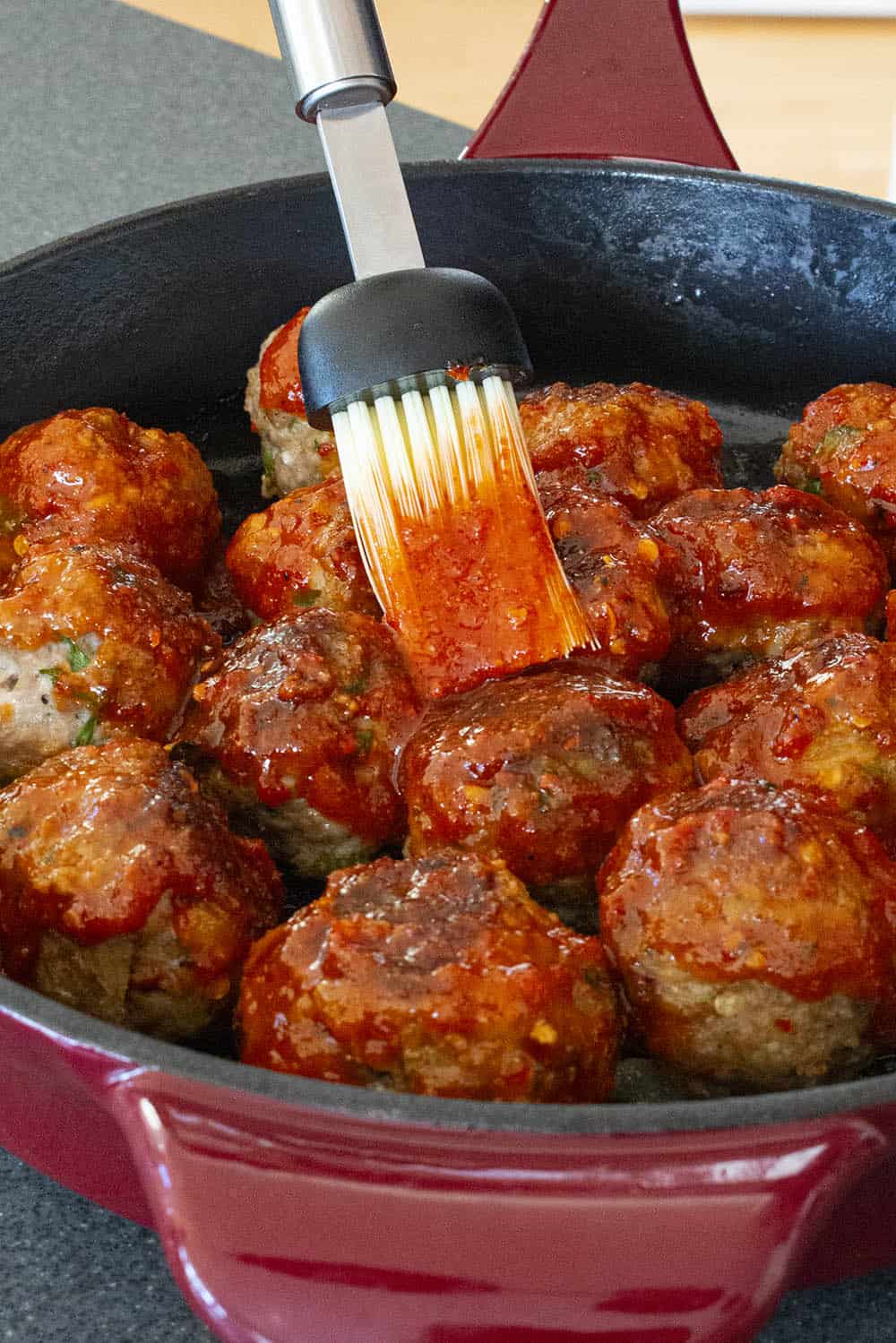 Brushing the honey-sriracha glaze over the turkey meatballs