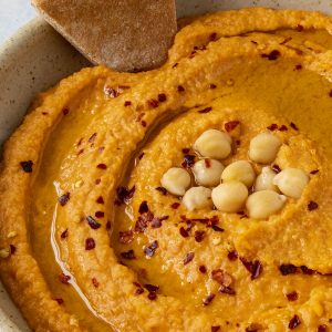 Roasted Red Pepper Hummus with a chip in the bowl