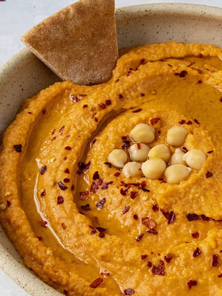 Roasted Red Pepper Hummus with a chip in the bowl
