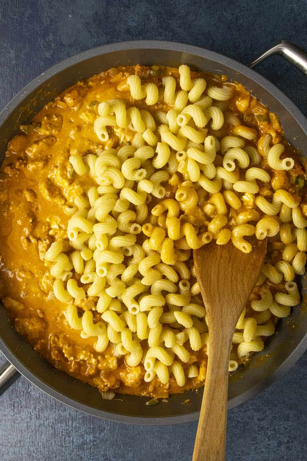 Stirring the noodles into the pan with the sauce.