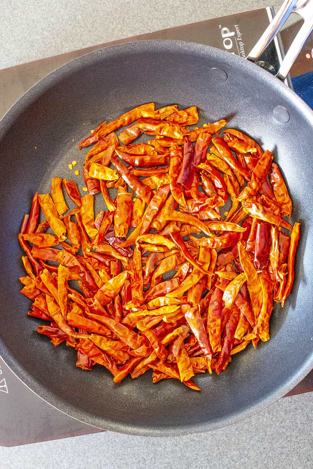 Chile de Arbol peppers being lightly toasted in a dry pan