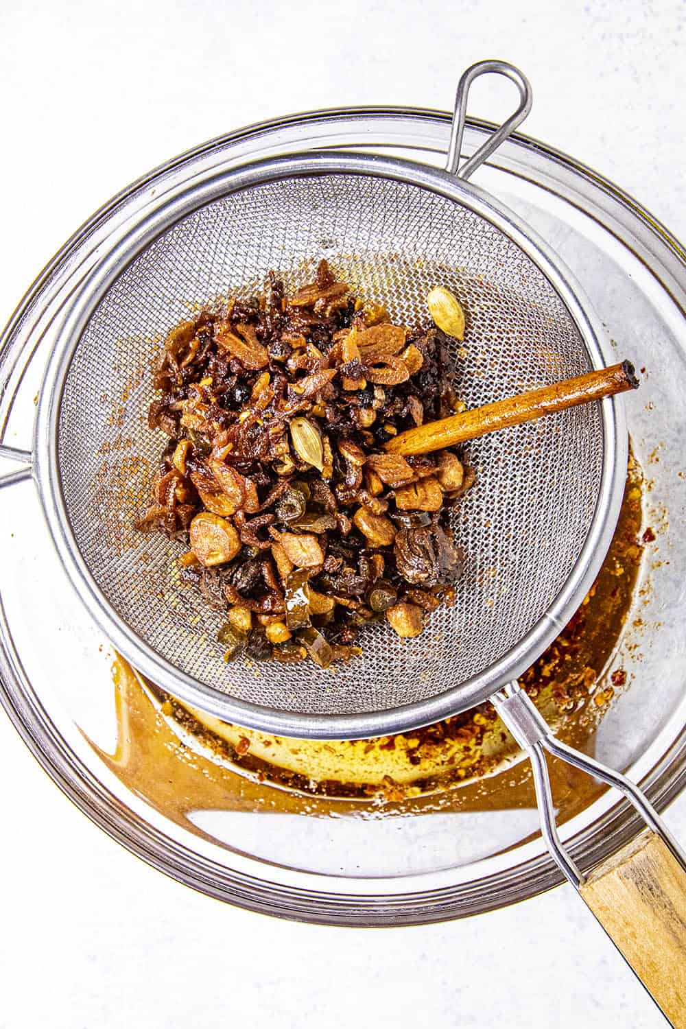 Straining the crisped bits of homemade chili crisp