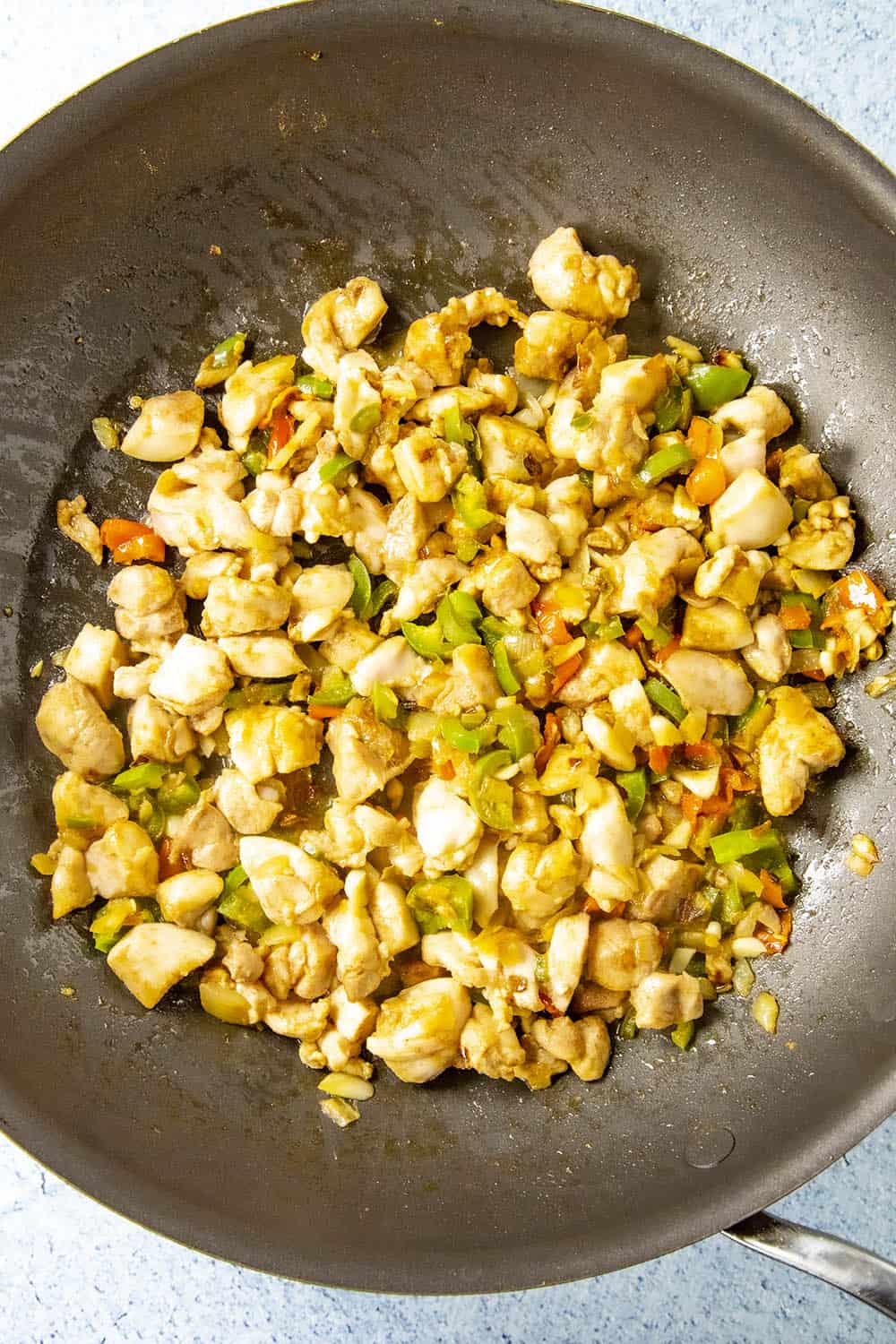 Cooking down the chicken in a pan with the peppers and onions