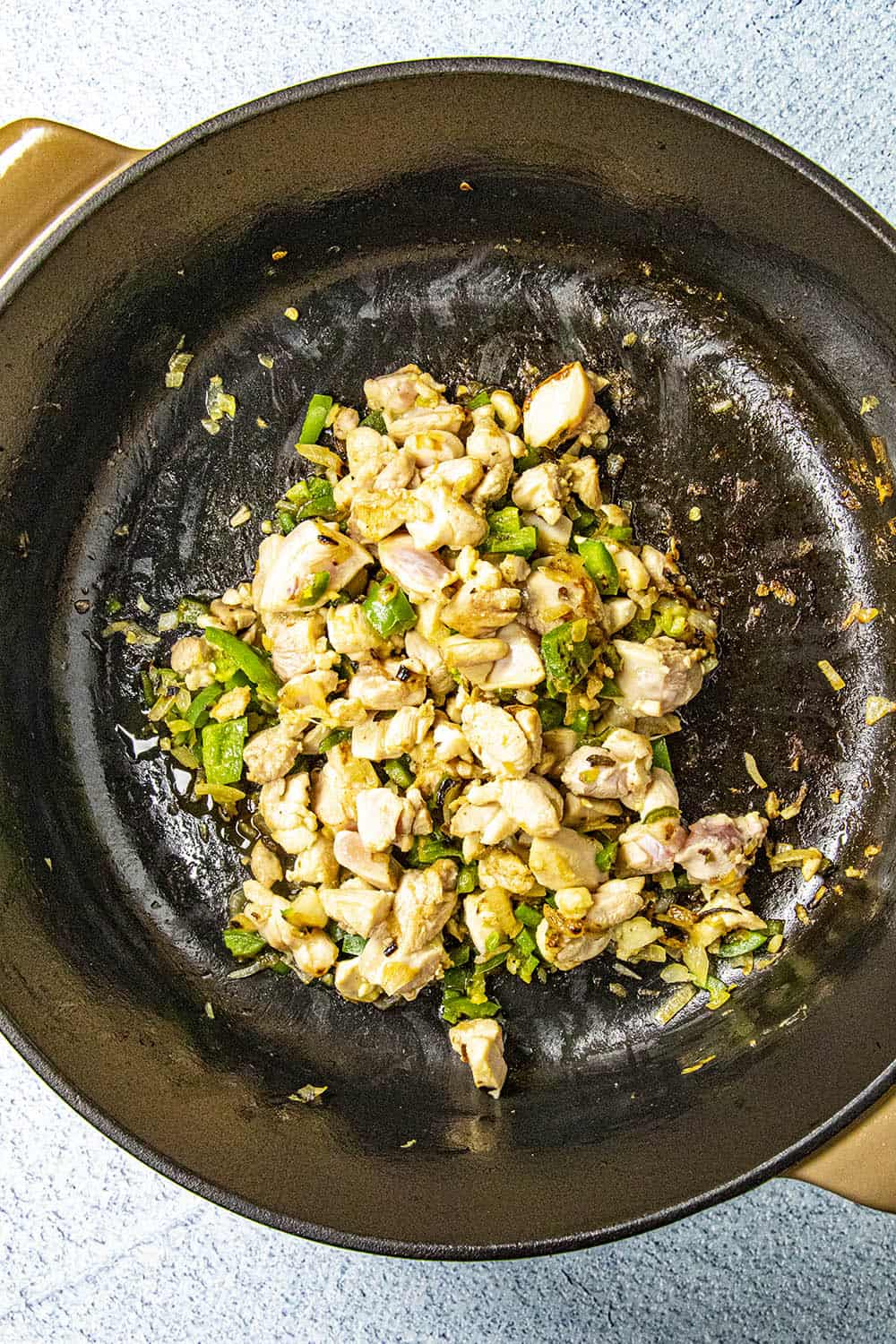 Cooking down the chicken, peppers and onion in a pot