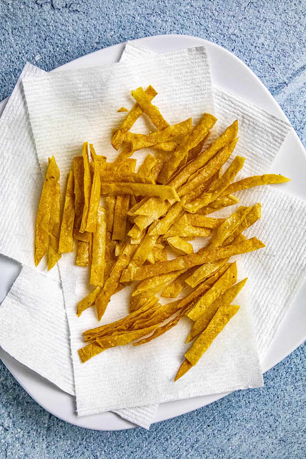 Crispy homemade fried tortilla strips draining on a plate