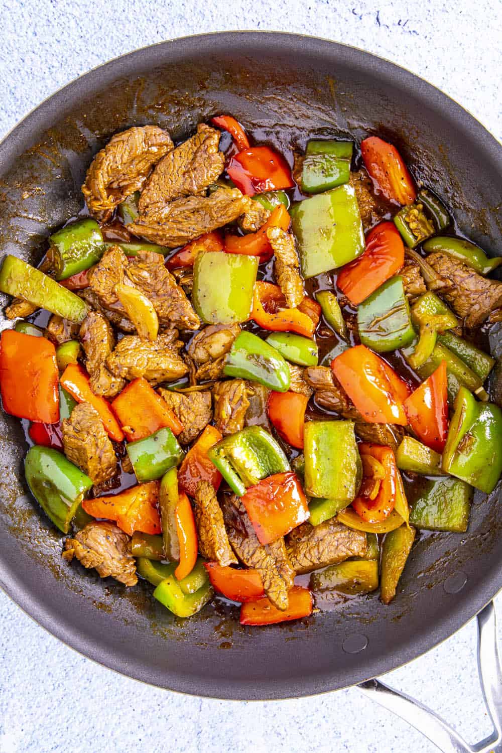 Combining the steak with peppers and sauce in a hot pan
