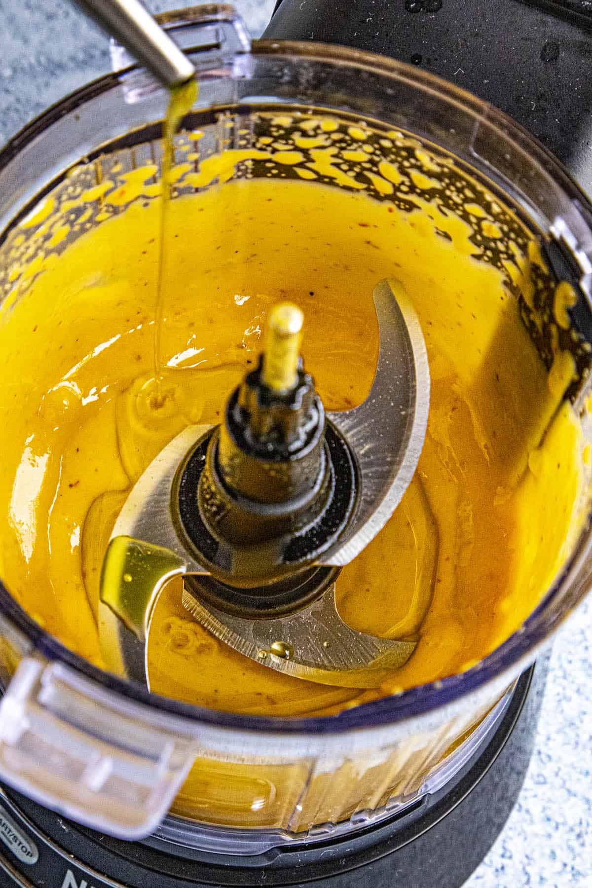 Slowly drizzling oil into the food processor to make sriracha aioli