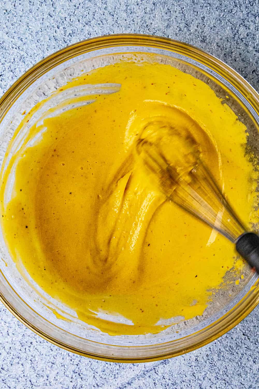 Vigorously whisking sriracha aioli in a bowl