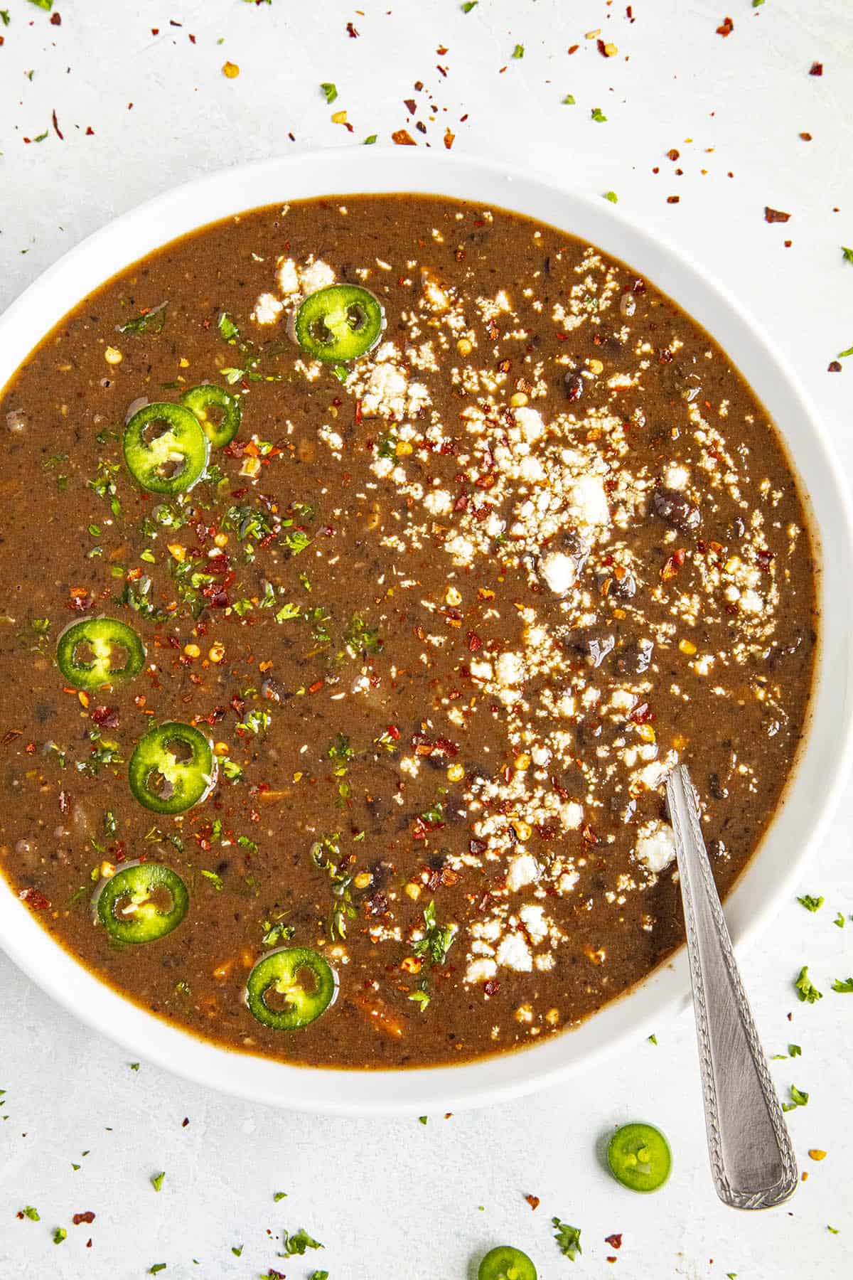 Black Bean Soup garnished with sliced peppers and crumbly white cheese