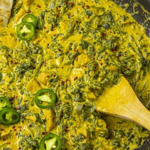 Chicken Saag in a hot pan with a serving spoon