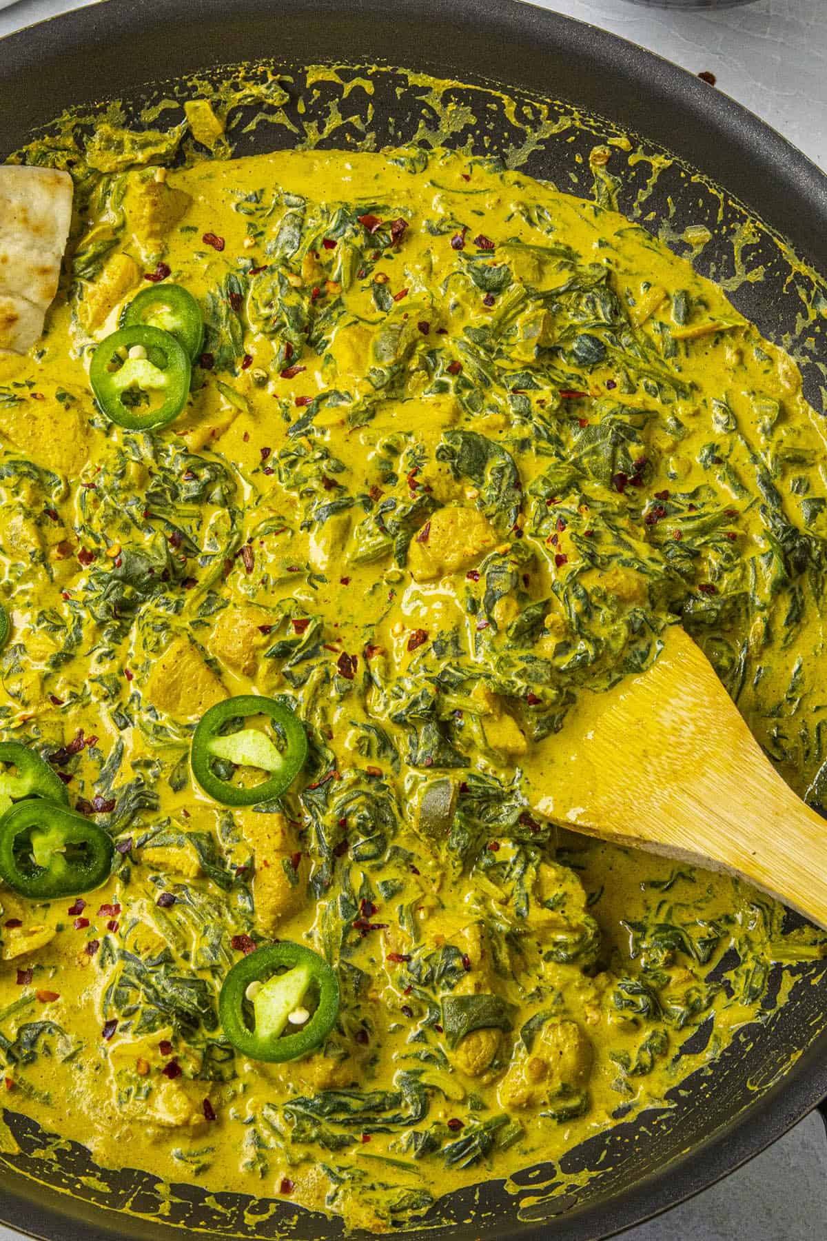 Chicken Saag in a hot pan with a serving spoon