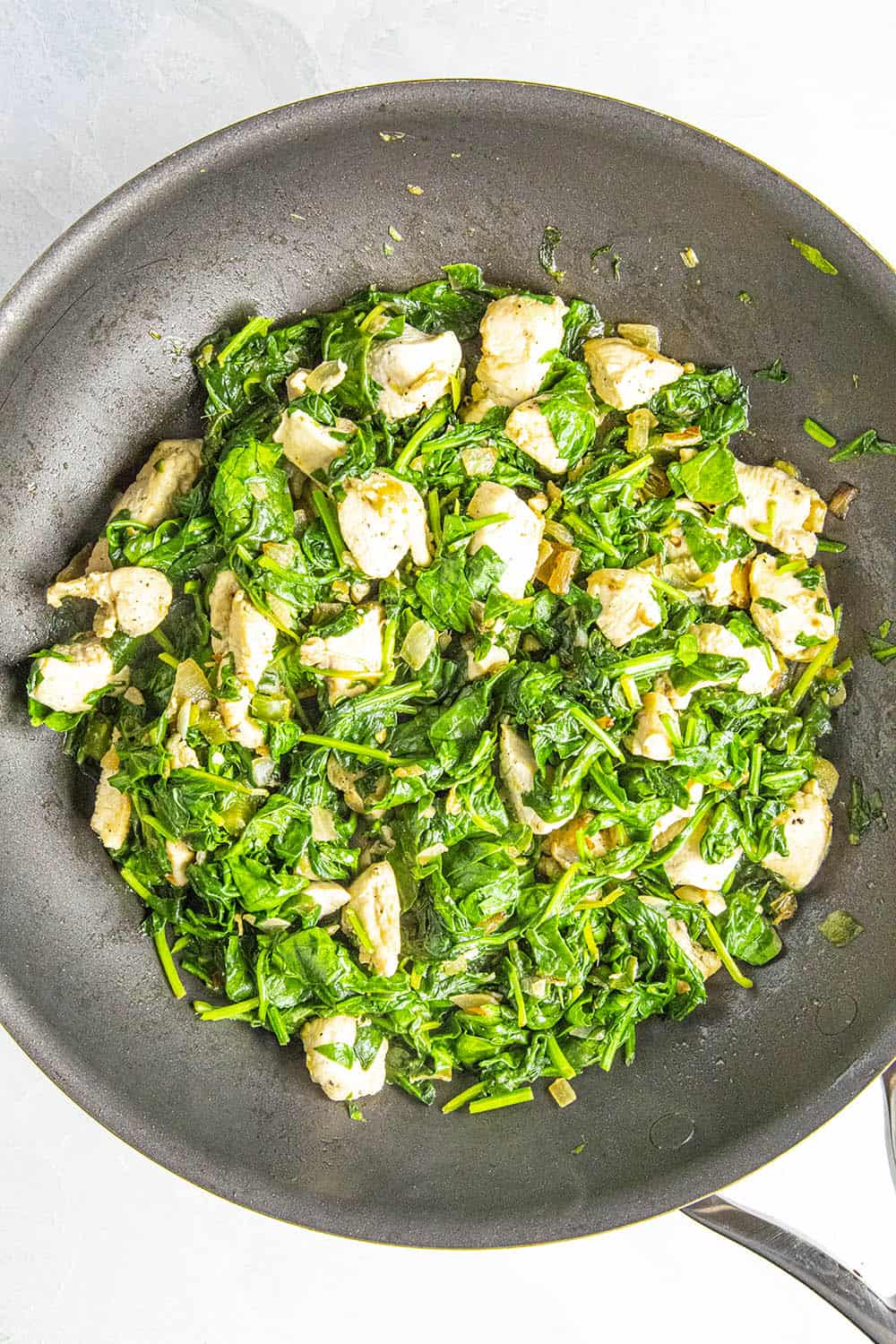 Adding spinach to the pan for chicken saag