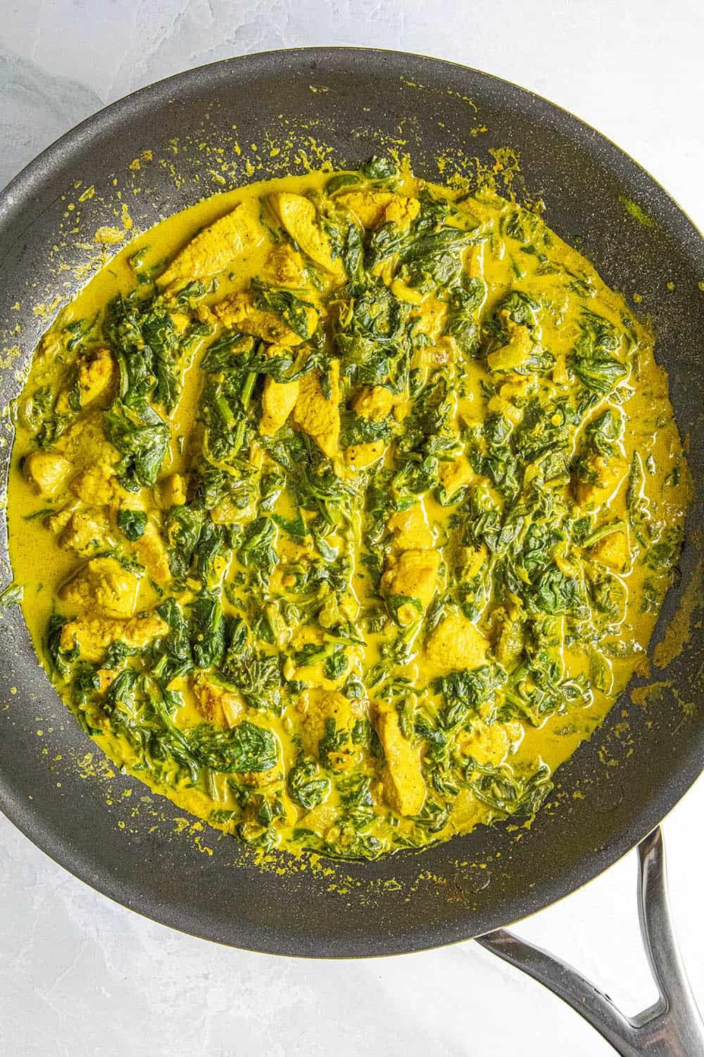 Simmering the chicken saag in a pan
