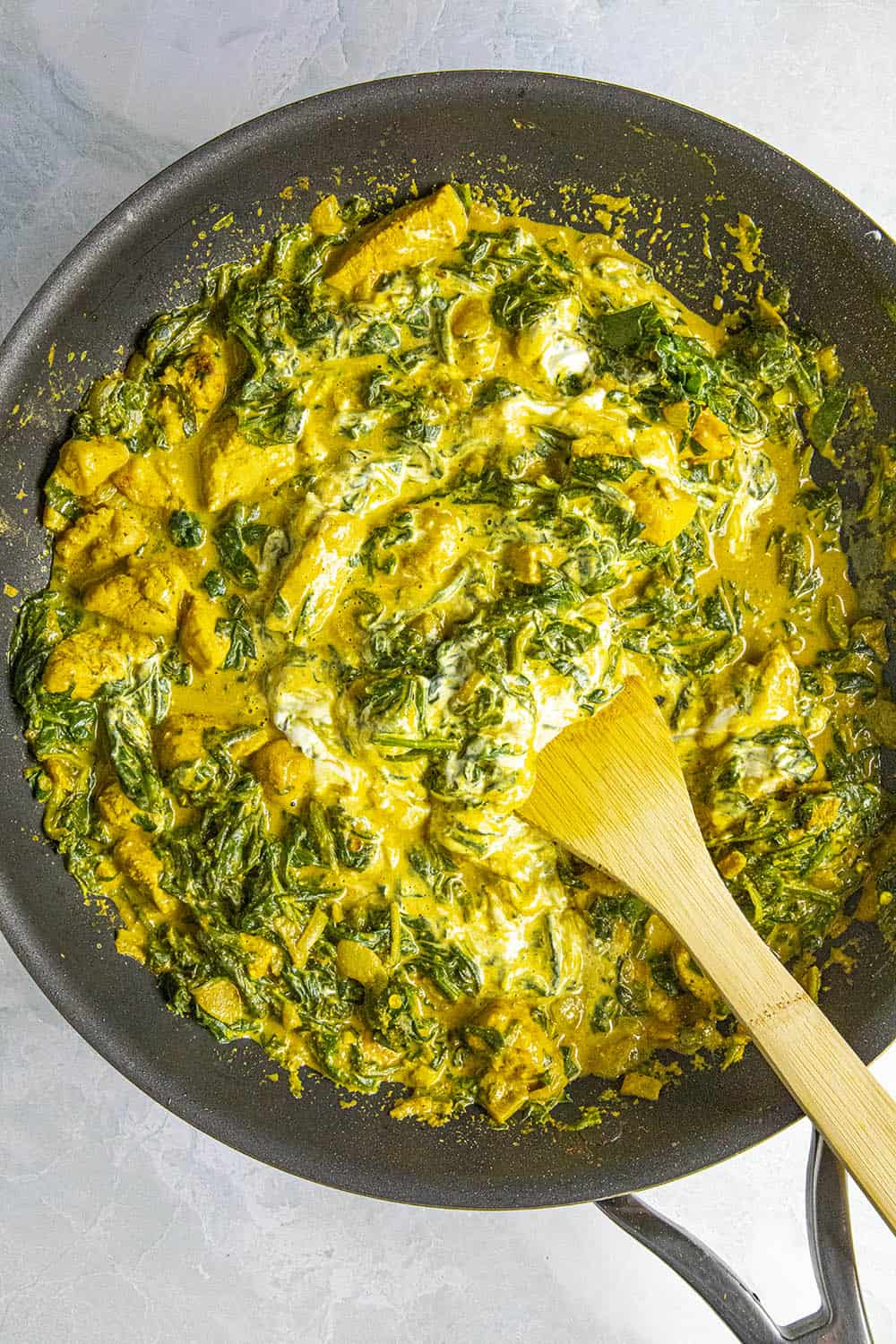 Stirring yogurt into the chicken saag