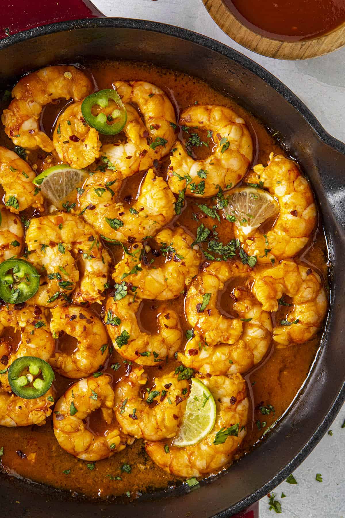 Spicy Firecracker Shrimp in a pan with sliced peppers and lime wedges