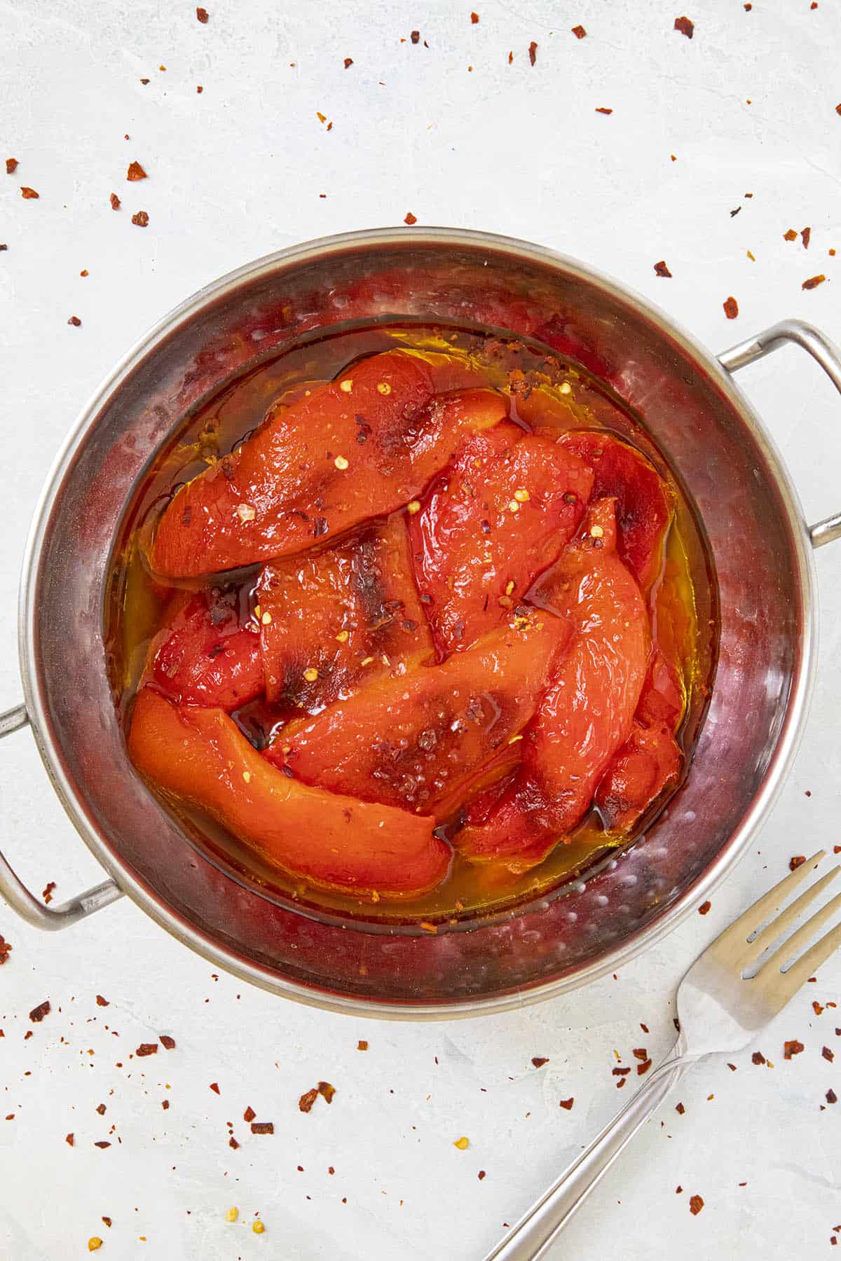 Roasted Red Peppers in a bowl with lots of olive oil, sprinkled with chili flakes