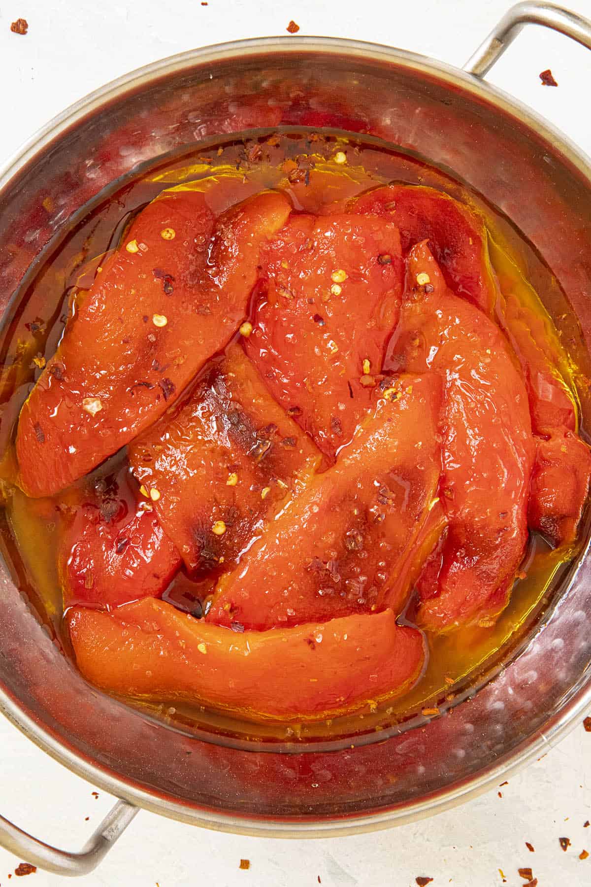 Roasted Red Peppers in a bowl with lots of olive oil, sprinkled with chili flakes