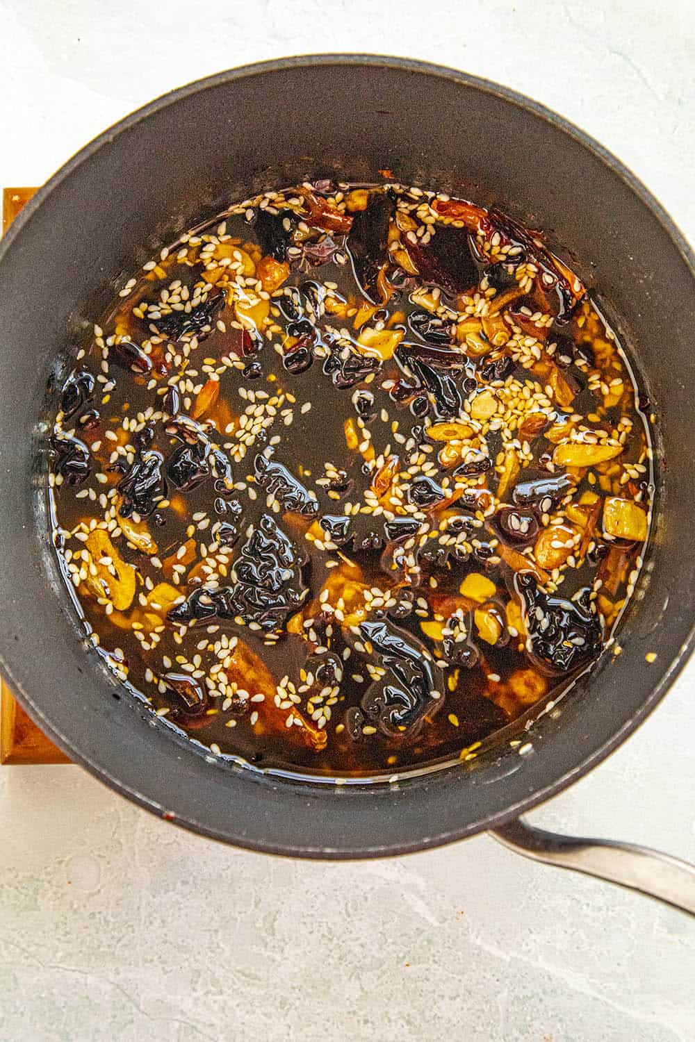 Cooking down the chili peppers in the hot oil with the sesame seeds, nuts and garlic