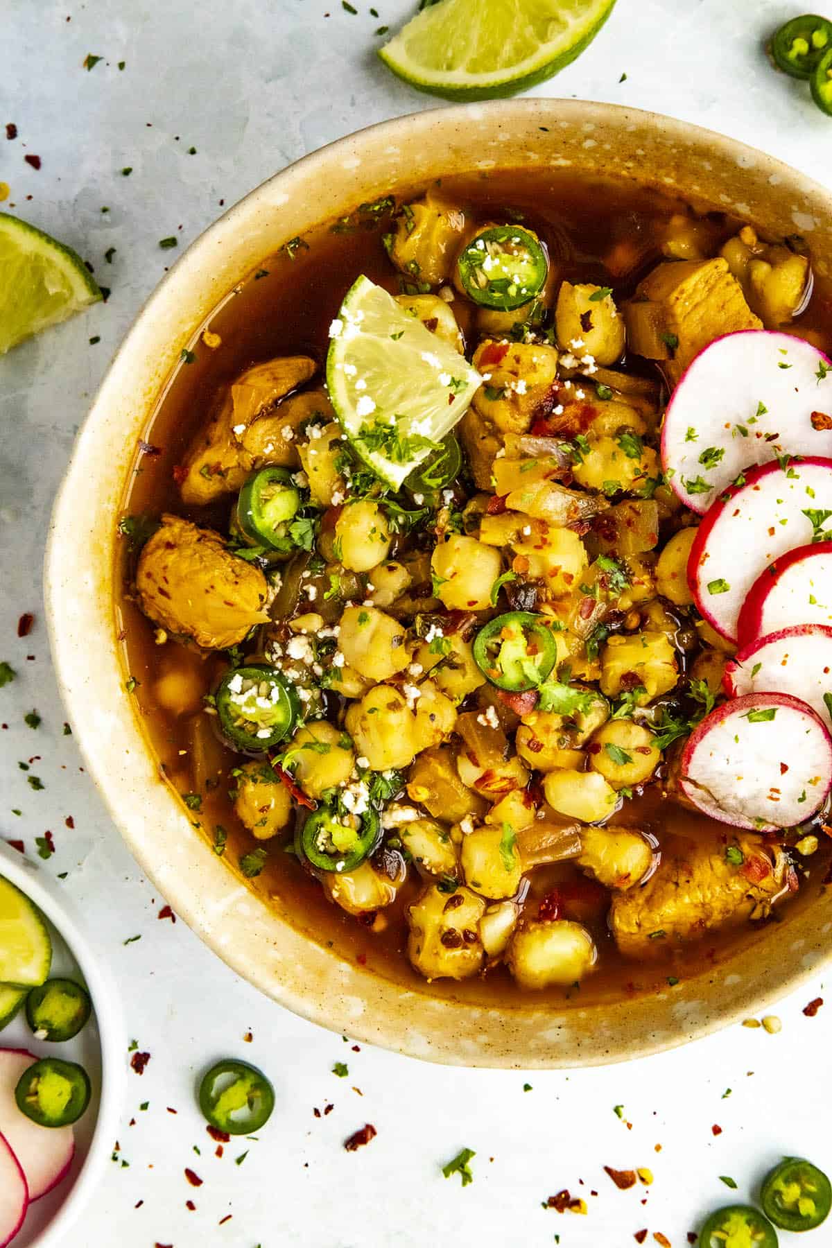 Chicken Pozole Rojo in a bowl, garnished with peppers and radishes