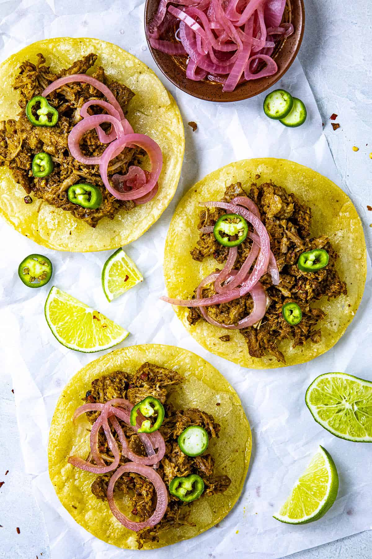 Three Cochinita Pibil Tacos with pickled onions and sliced peppers