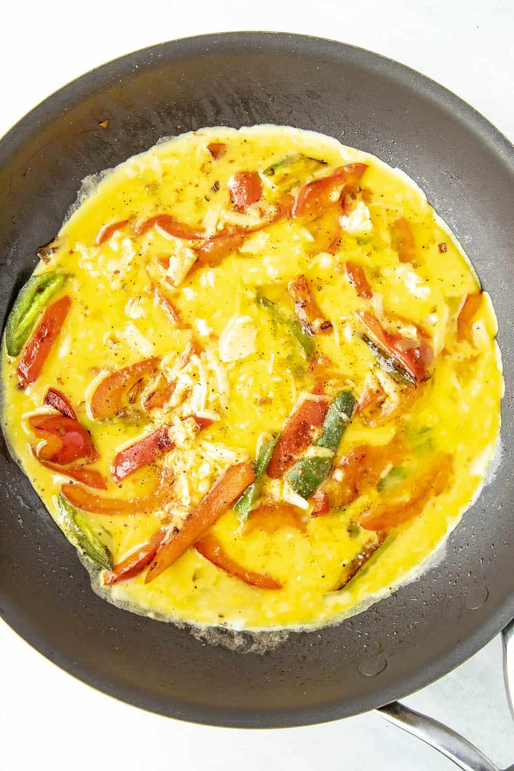 Eggs setting in a pan with lots of peppers