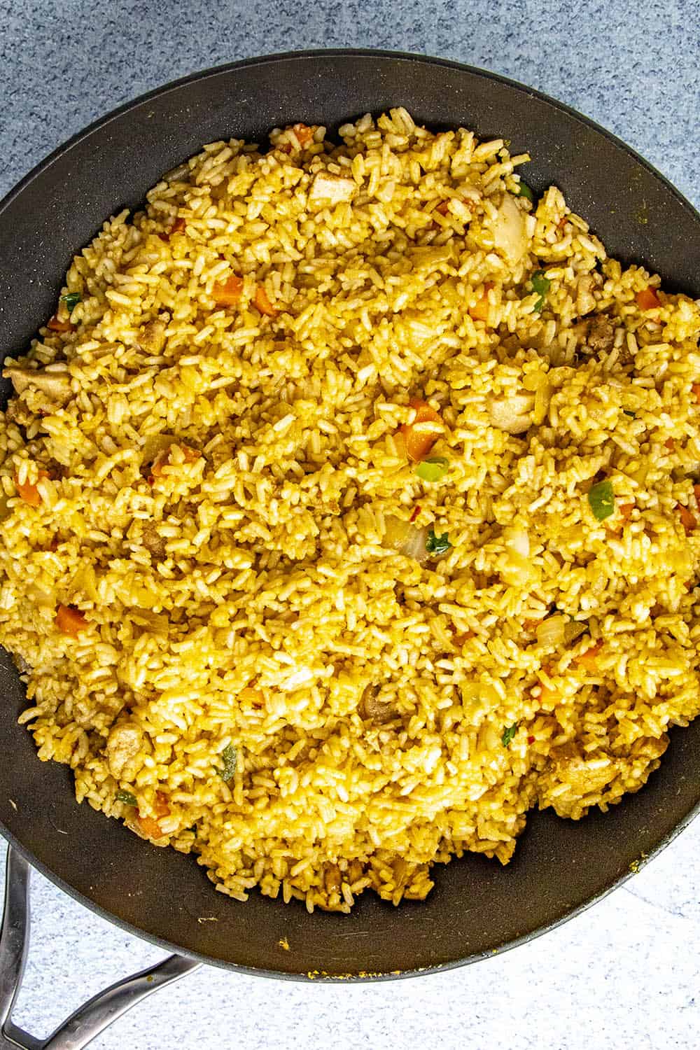 Adding the cooked rice to the hot pan with the chicken and vegetables