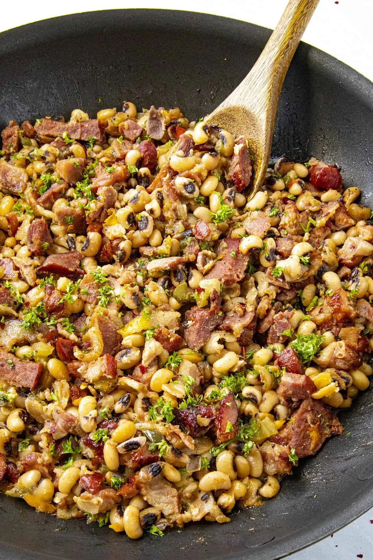 Taking a scoop of Black Eyed Peas from the pan