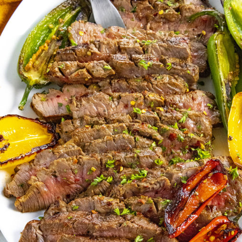 Serving sliced London broil on a platter with grilled peppers
