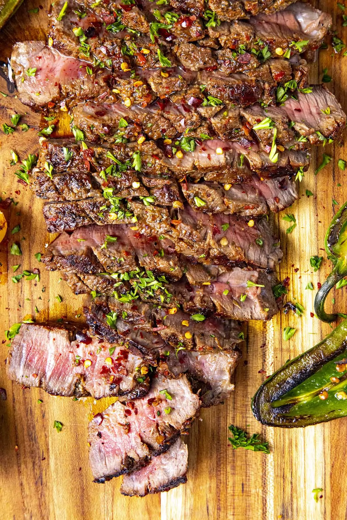 Sliced London broil on a platter with chili flakes