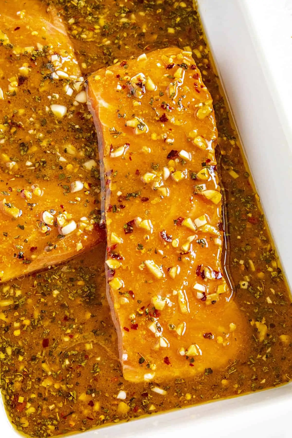 Slices of pink salmon marinating in a bowl of spicy salmon marinade